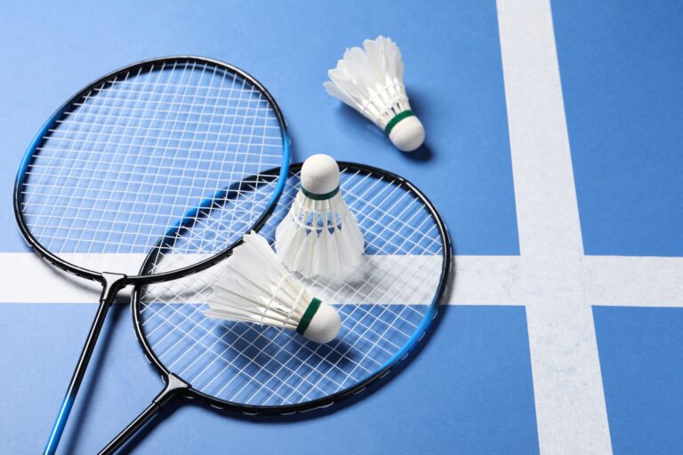 Feather,Badminton,Shuttlecocks,And,Rackets,On,Blue,Background.,Space,For